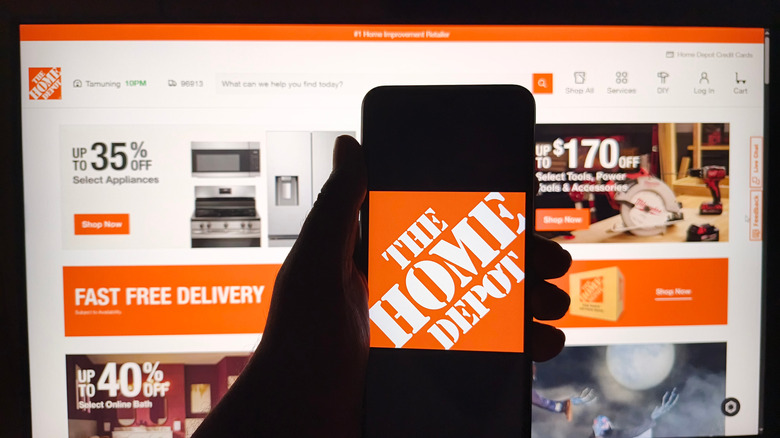 Home Depot website pulled up on screen with smartphone in view displaying Home Depot logo