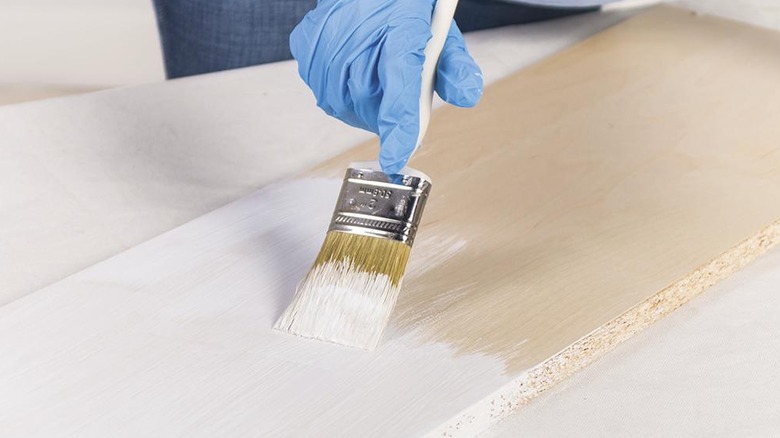 Someone painting on a piece of wood.