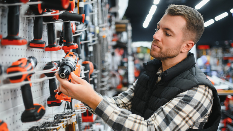 A man looking at power drills in a hardware store.