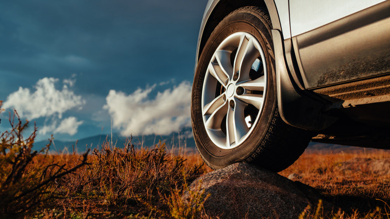 A car's tire climbing over a rock while off-roading