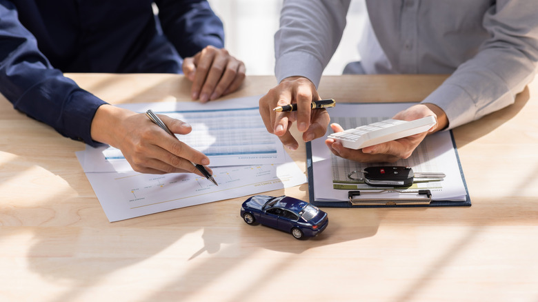 A person going over warranty information with a salesman at a dealership