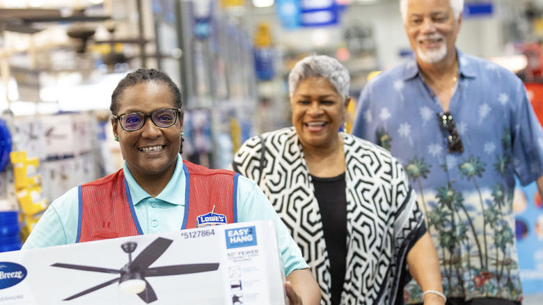 Lowe's store employee walking with customers to buy a ceiling fan