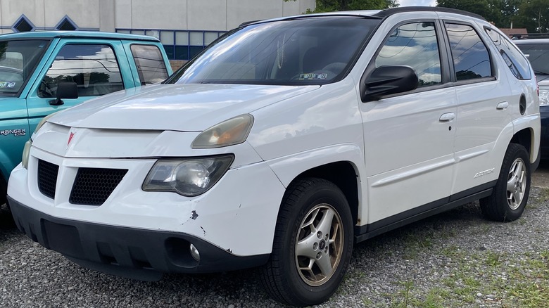 White 2004 Pontiac Aztek parked on gravel with other vehicles