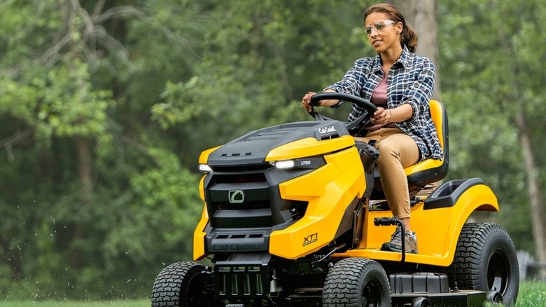 A woman mowing the grass with aboard a Cub Cadet XT1 riding mower.