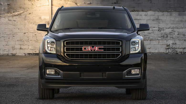 A GMC Yukon parked in front of a brick wall