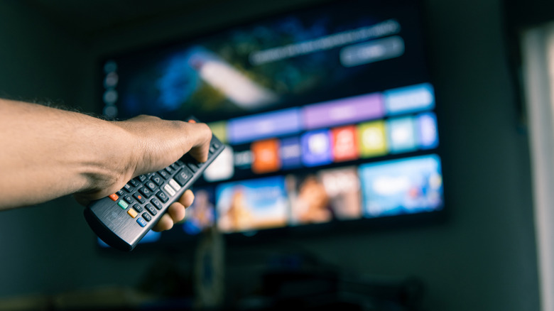 Hand holding a remote control, browsing streaming services on a smart tv