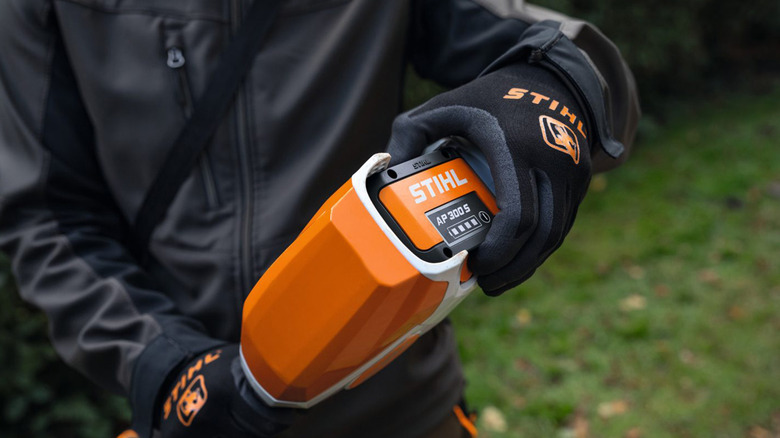 A man removing the battery of his Stihl string trimmer