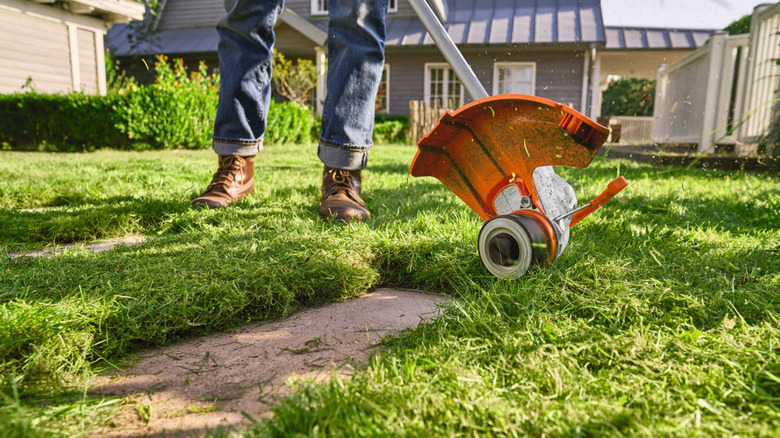 A man using a Stihl string trimmer sideways.