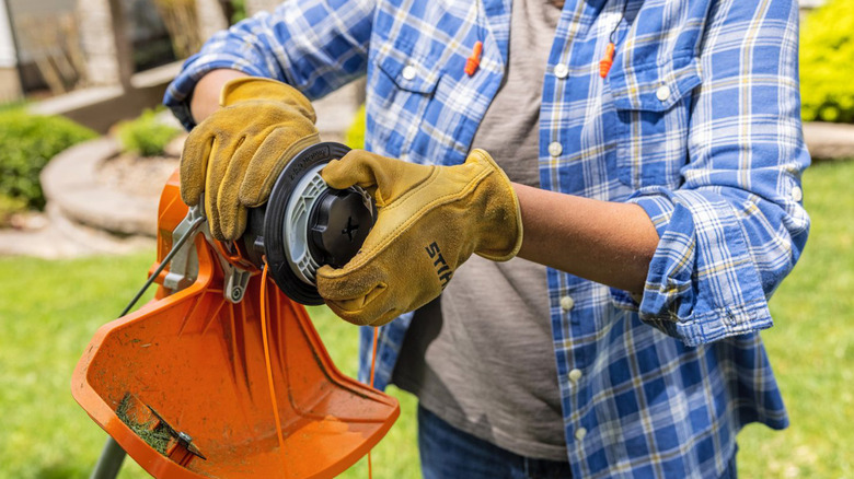 A woman replacing the head of a Stihl string trimmer.