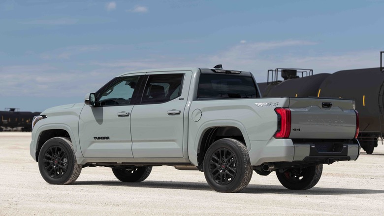 A back 3/4 shot of  a Grey Toyota Tundra parked on gravel.