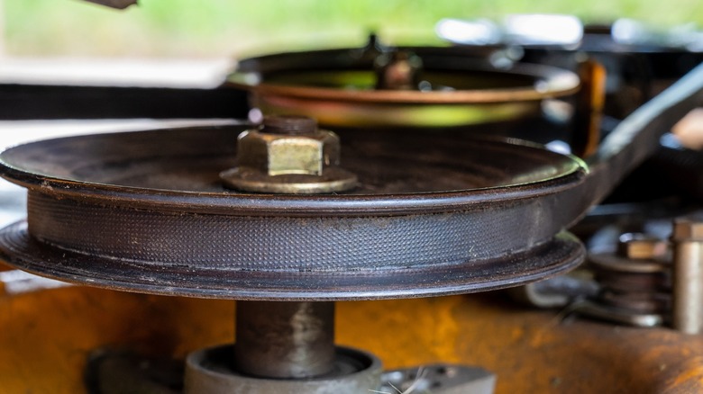 The belt and pulleys of a riding lawn mower deck.
