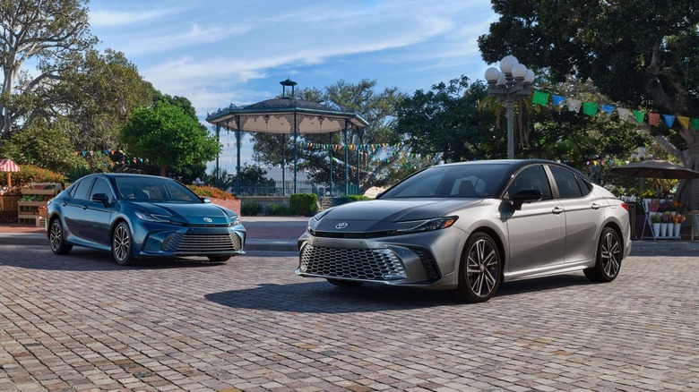 Two Toyota Camry sedans parked on cobbles inside a park.
