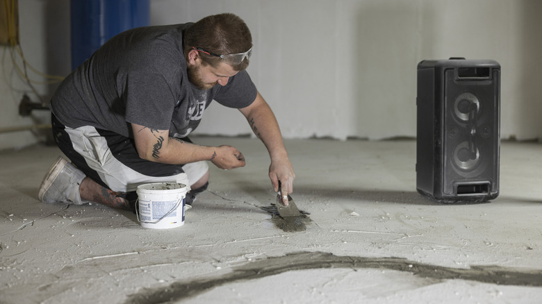 A man with a bucket on his side sealing cracks