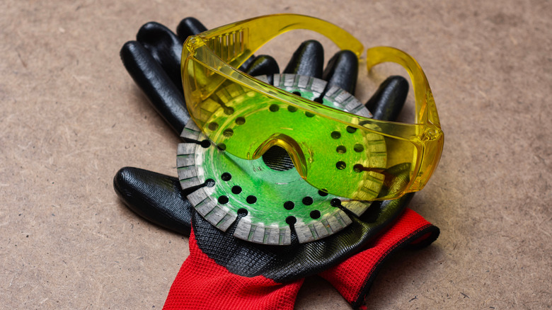 Yellow protective safety glasses, black and red work gloves, and a diamond cutting disc for angle grinder.
