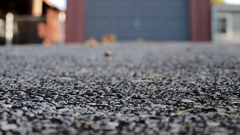 A close-up of an asphalt driveway in front of a garage.