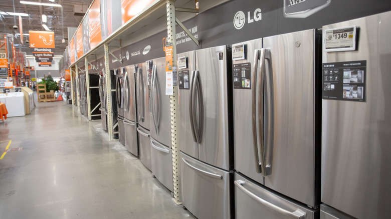 A row of several stainless steel bottom-freezer refrigerators in a retail showroom