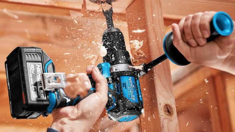 A Hercules 20V Brushless Cordless, 1/2 in. Drill/Driver Kit from Harbor Freight with side handle in use, drilling through wooden blocks