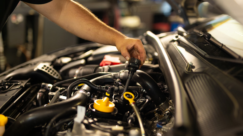 A mechanic performing maintenance under the hood of a vehicle