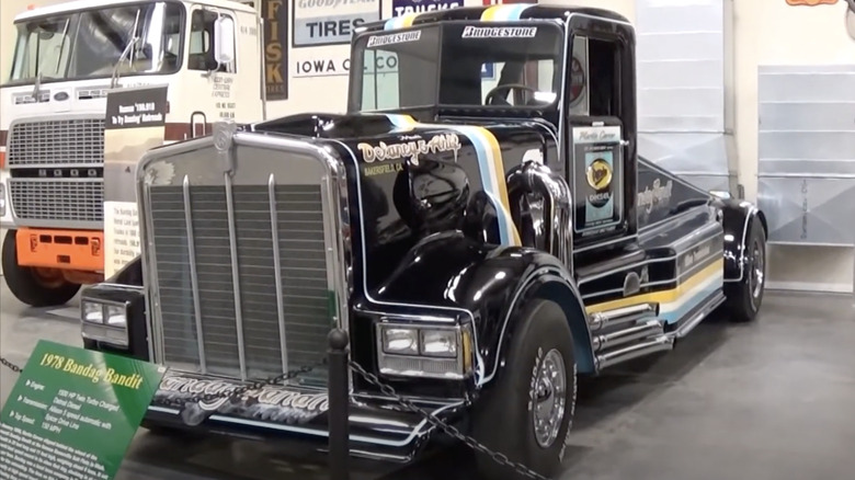 The 1978 Kenworth "Bandag Bandit" show truck on museum display, showing off its black paint with blue-gold stripes, huge chrome grille, and side pipes.