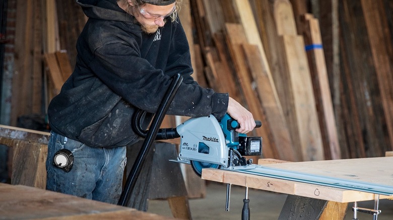 man using a Makita track saw to cut wood