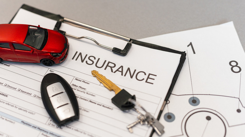 Car insurance paperwork with toy car and key fob