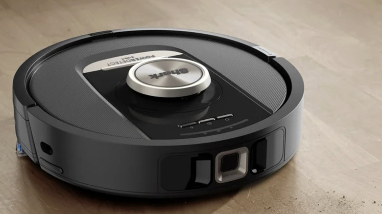 The Shark PowerDetect 2-in-1 Robot Vacuum & Mop with NeverTouch Pro Self-Cleaning Base on a wood floor cleaning visible dirt