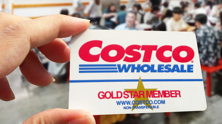 Close-up of a hand holding a Costco Gold Star membership card inside a Costco store
