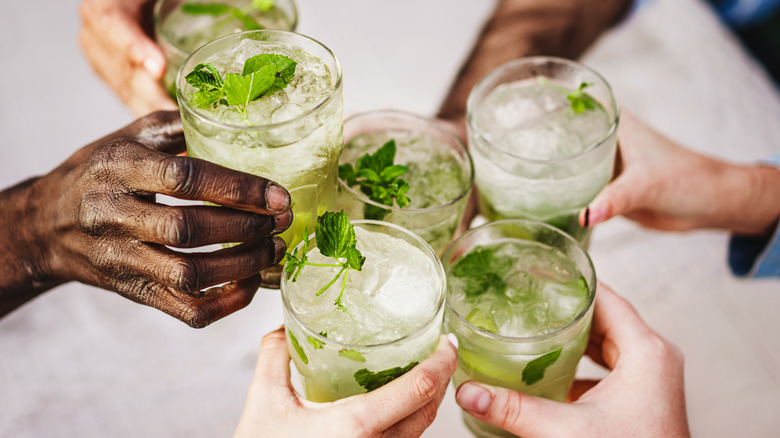Closeup of people hands holding cocktails with ice