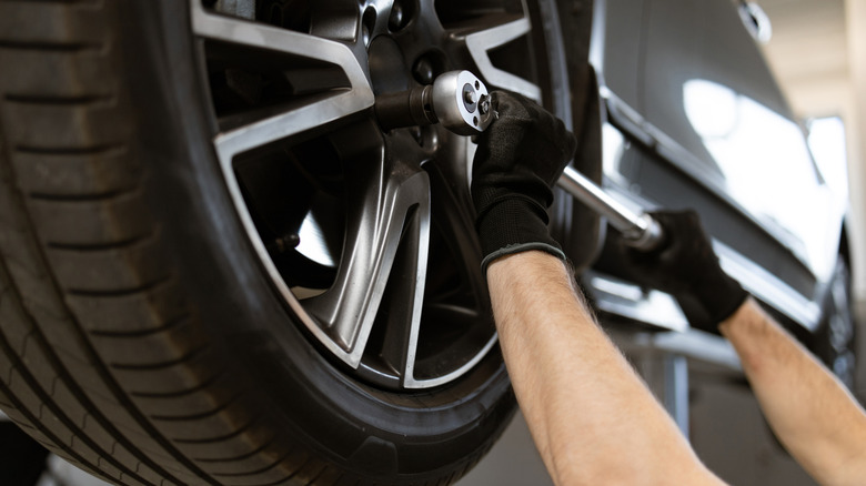 A mechanic tightening the lug nut of a car wheel.
