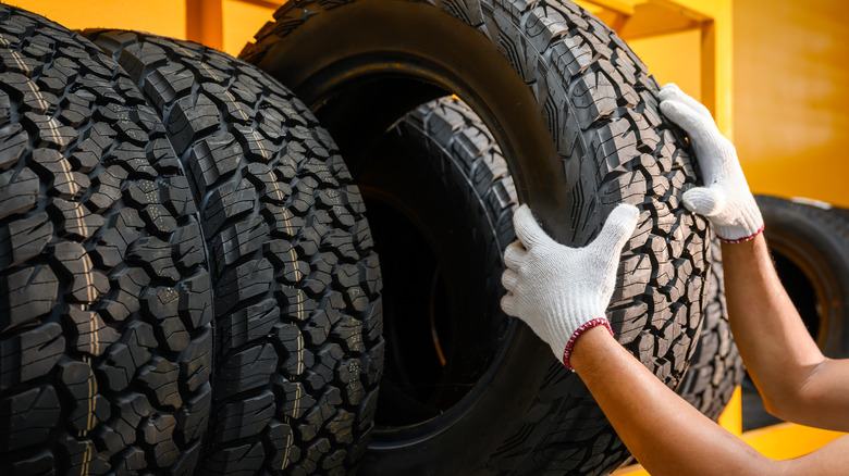 Person with gloves lifting a tire from a rack