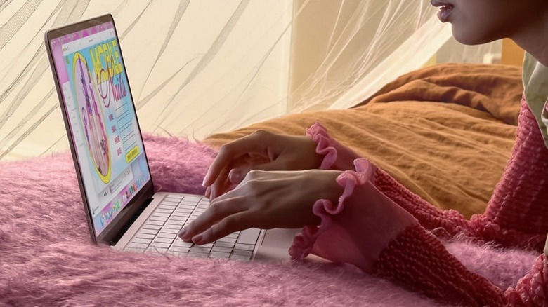 Hands typing on a MacBook Neo on a bed