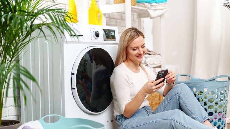 woman in laundry room using phone