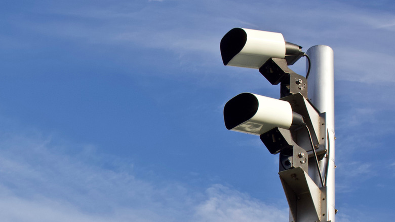 Two automatic license plate reader cameras on a pole on a blue sky.