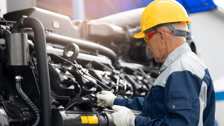 Mechanic with tablet computer working on a diesel engine