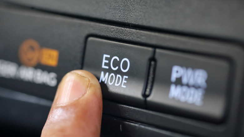 Finger pushing Eco Mode button on the center console of a car