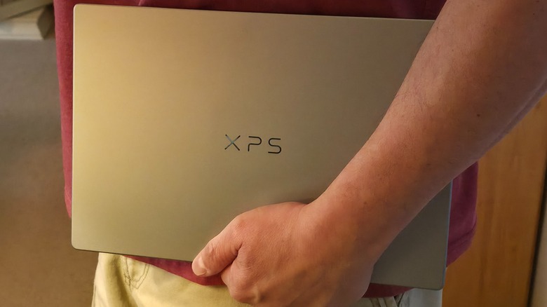 A man holding a Dell XPS 13 on his side