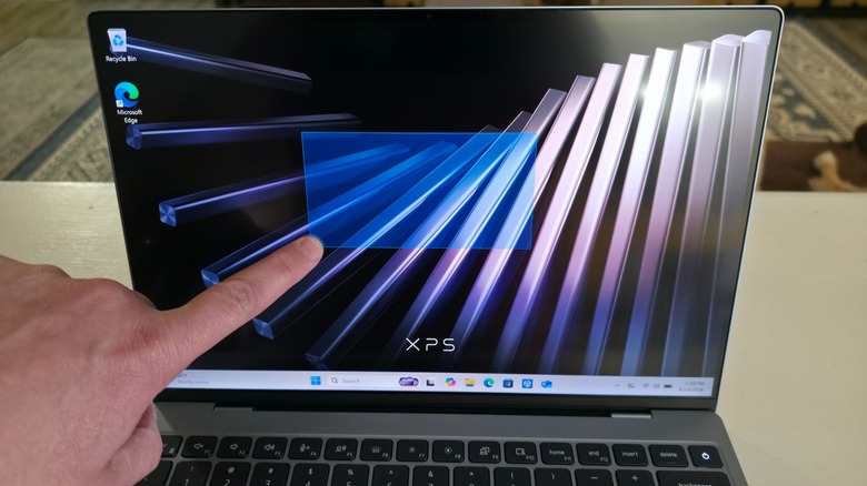 A man's hand using a touchscreen laptop to draw a rectangle