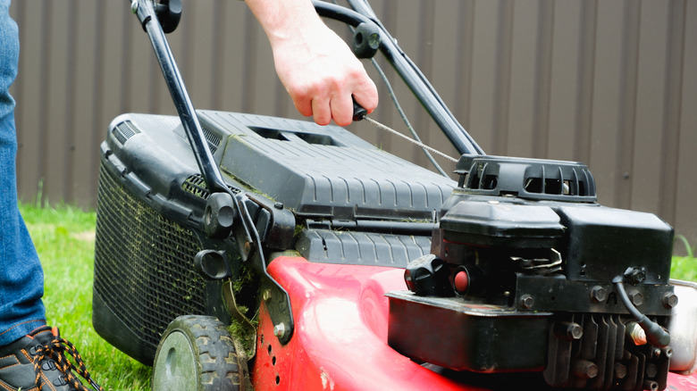 A person starting their lawn mower.