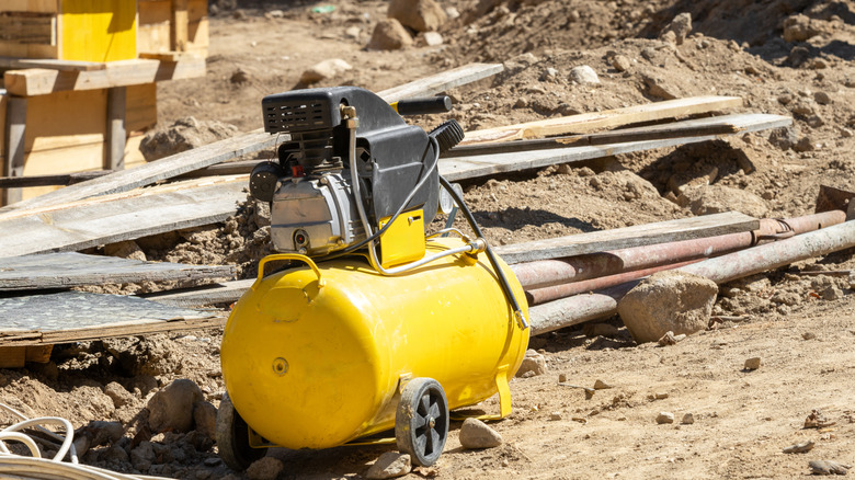 Yellow air compressor at construction site.