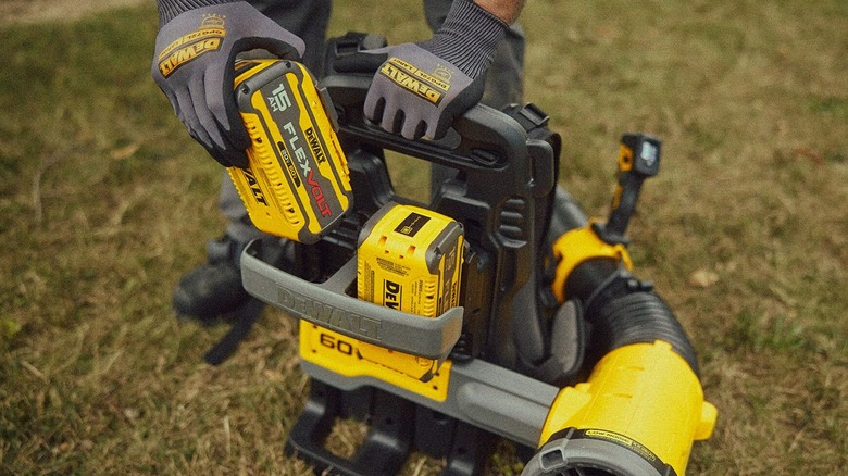 A person putting batteries into a DeWalt blower.