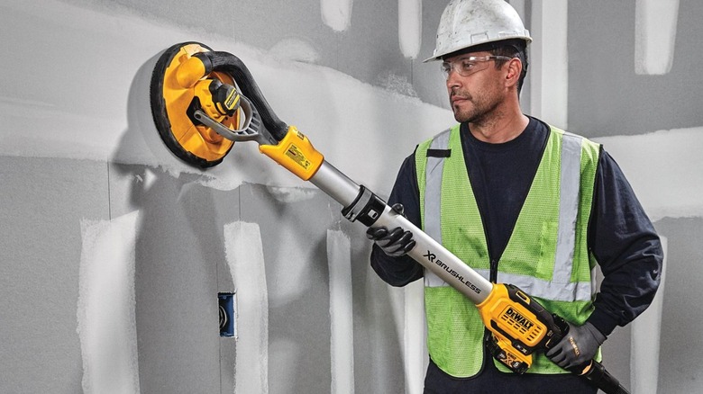 Worker using DeWalt Drywall Sander on grey wall
