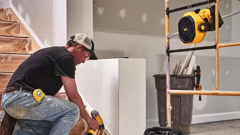 Man working with DeWalt tool with fan hanging nearby