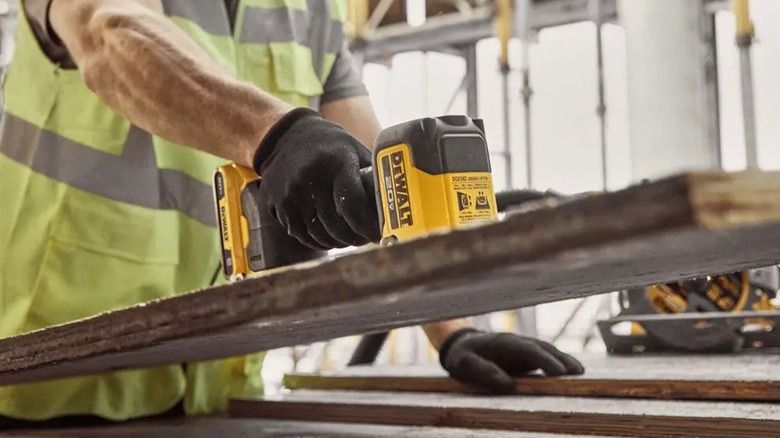 A person using a DeWalt Grabo suction lifter to lift a wood plank.