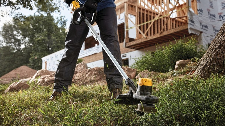 A person using a cordless DeWalt string trimmer.