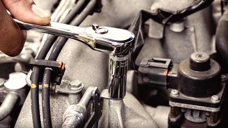 Person using a DeWalt socket wrench to work on a car engine