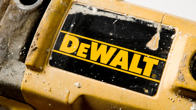 A DeWalt logo on an unidentified tool with some dirt surrounding it