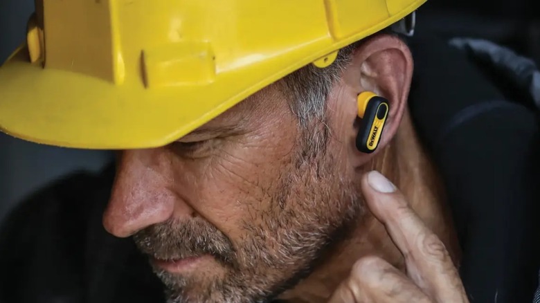 Man with yellow work helmet wearing DeWalt earbud