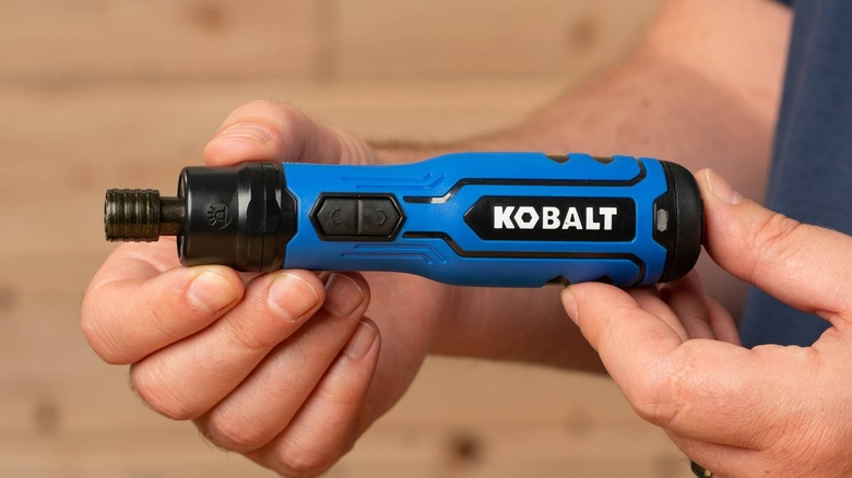 A person holding a cordless Kobalt screwdriver.
