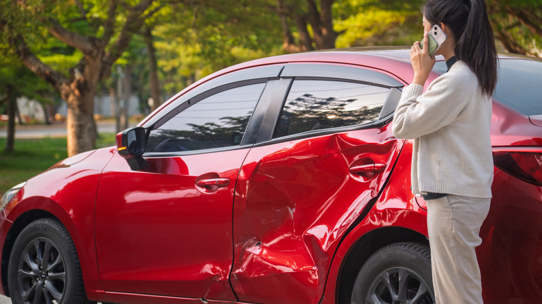 Woman on phone next to damaged car