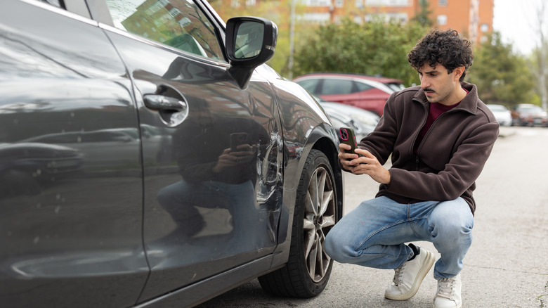 man taking pictures of car damage
